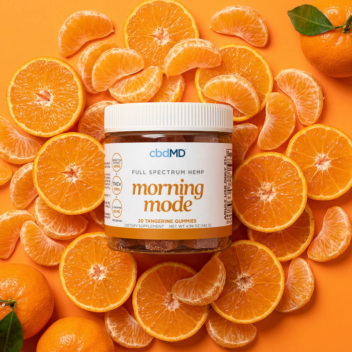cbdMD Morning Mode Tangerine Gummies jar surrounded by fresh orange slices.