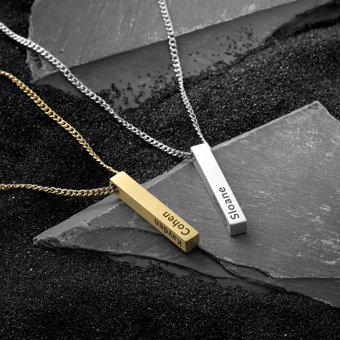 Two necklaces with bar pendants on a dark surface