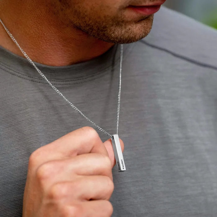 Man wearing a silver necklace with a rectangular pendant.