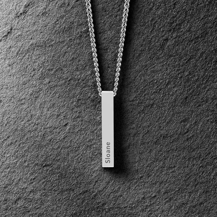 Silver necklace with a bar pendant on a dark gray textured background
