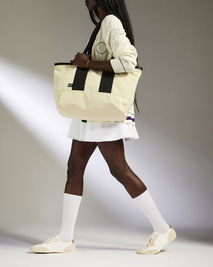 a woman in a white skirt and white sweater carrying a bag