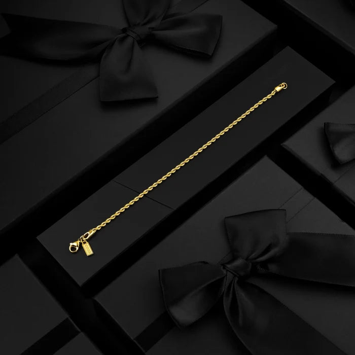 Gold bracelet on a black gift box with ribbons