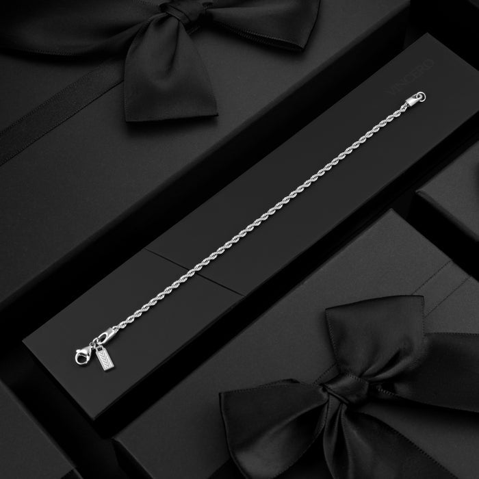 Silver bracelet on a black surface with black ribbons