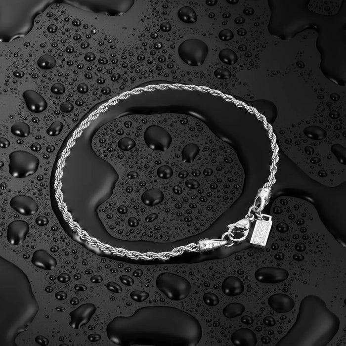 Silver bracelet on a dark surface with water droplets