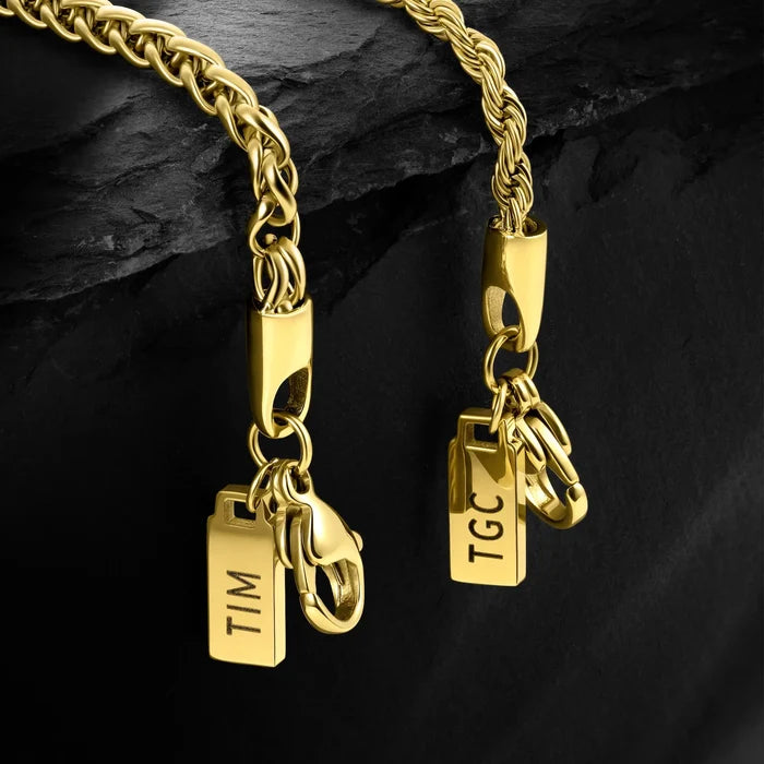 Gold chain necklace with two pendants on a dark stone background