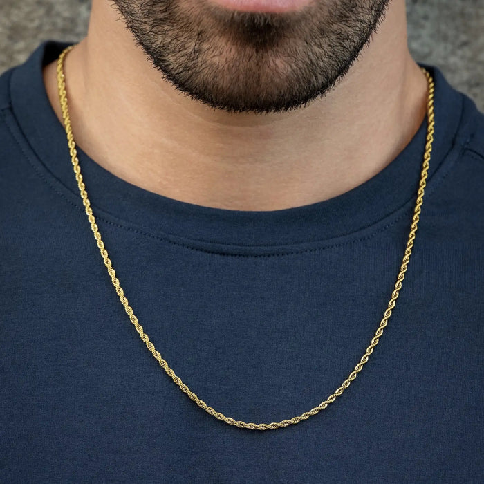 Gold chain necklace worn by a person on a plain background
