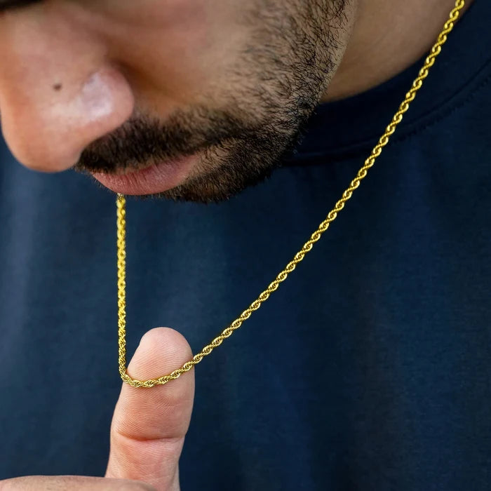 Close-up of a gold chain held by a person against a dark background