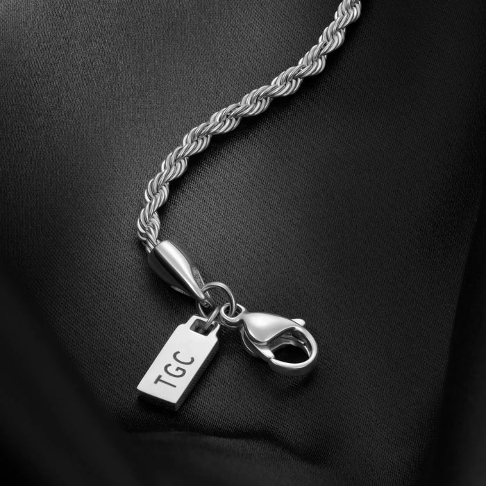 Silver necklace with a tag and clasp on a black background