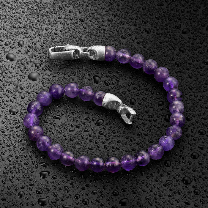 Purple beaded bracelet with silver clasp on a wet black surface