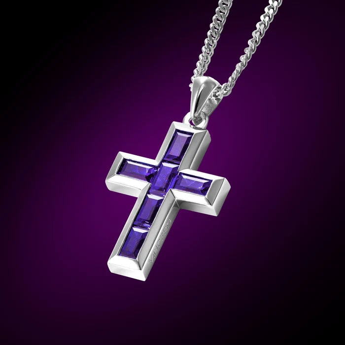 Silver cross pendant with purple stones on a chain against a purple background
