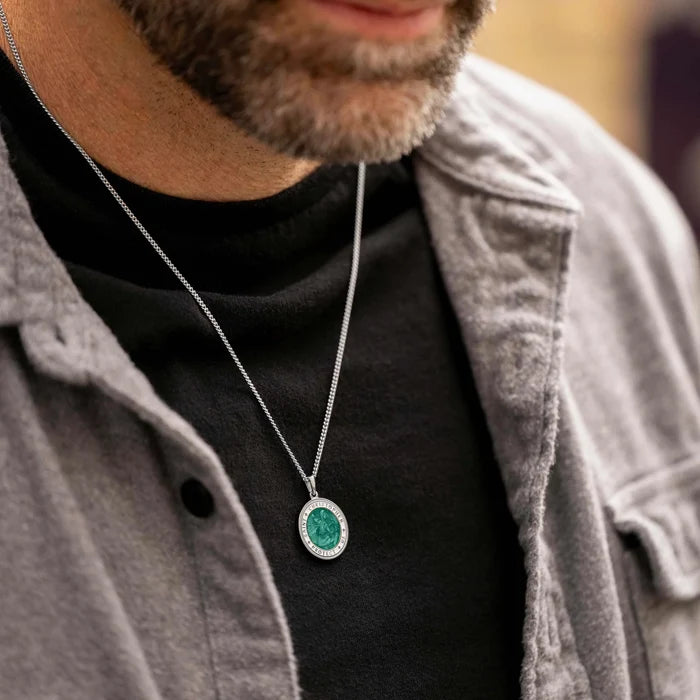 Person wearing a necklace with a green pendant