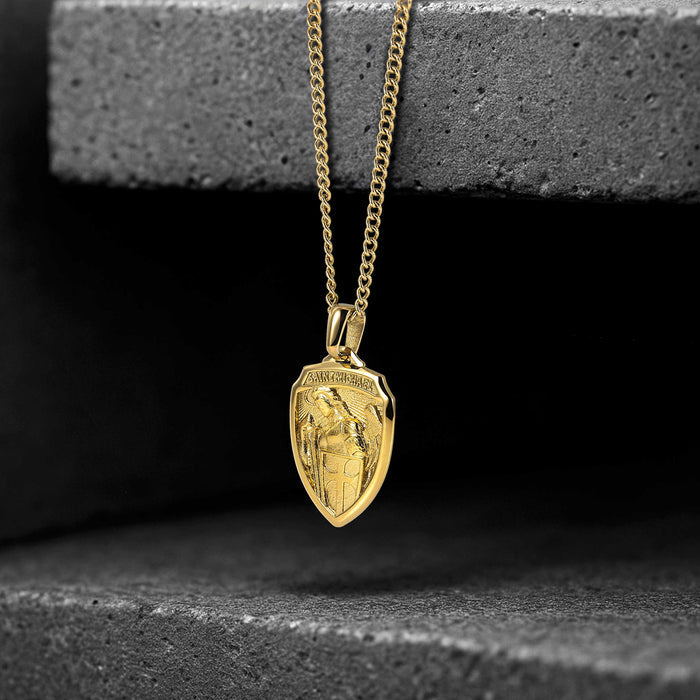 Gold necklace with a shield-shaped pendant on a dark background