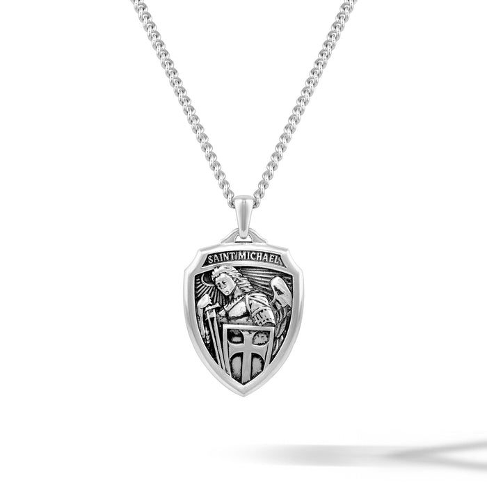 Silver necklace with a shield-shaped pendant featuring an engraved design on a white background