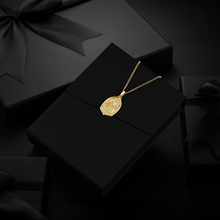 Gold necklace with a pendant on a black box against a dark background