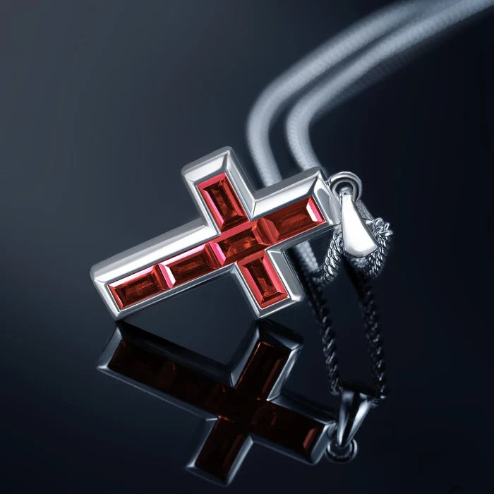Silver cross pendant with red gemstones on a dark background