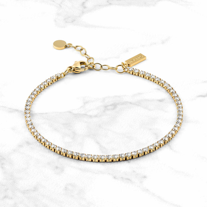 Gold bracelet with clear stones on a marble background