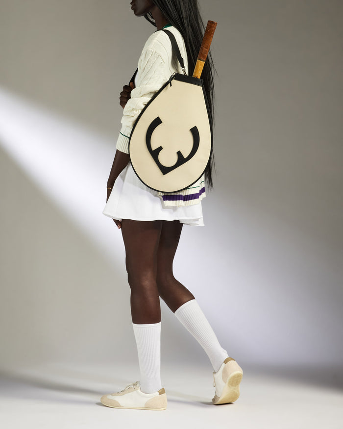 a woman in a white dress with a tennis racket