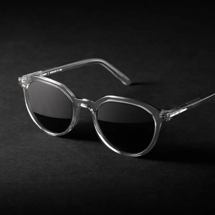 Sunglasses with clear frame and dark lenses on a black background