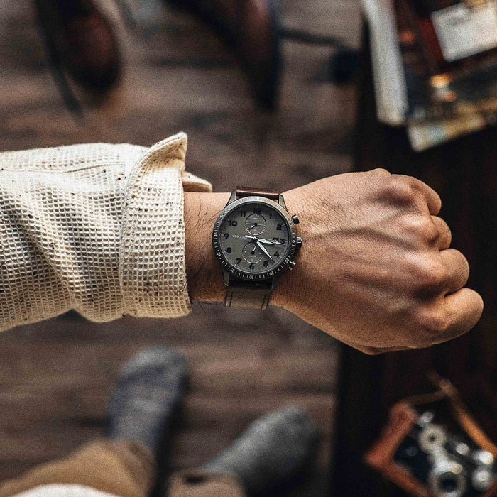 Person wearing a dark wristwatch with a blurred background