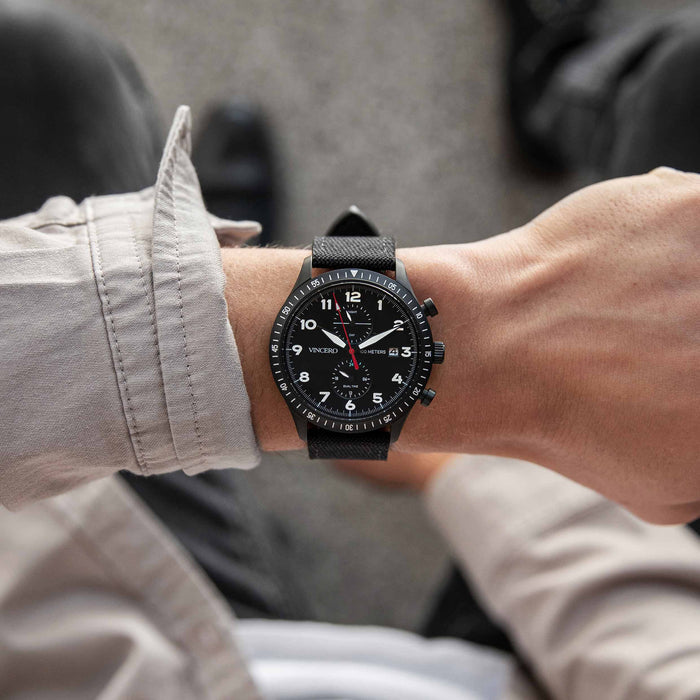 Person wearing a black wristwatch with a blurred background