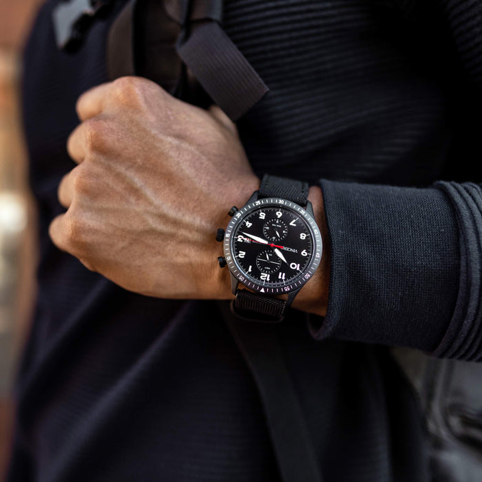 Person wearing a black wristwatch with a dark background