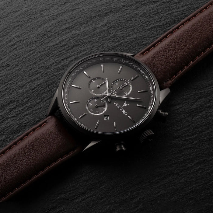 Wristwatch with brown leather strap and dark face on a dark background