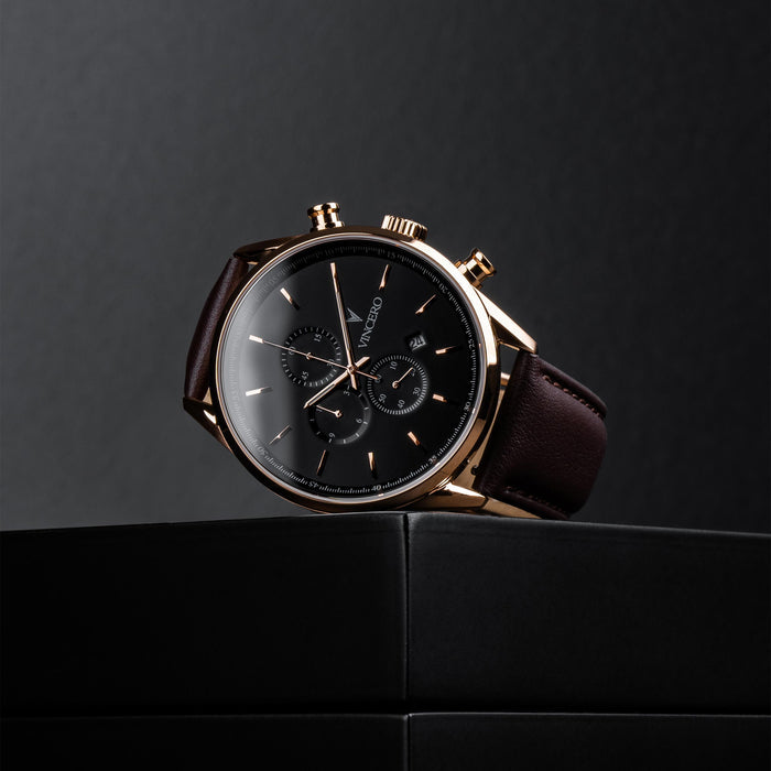 Luxury watch with black face and brown leather strap on a dark background