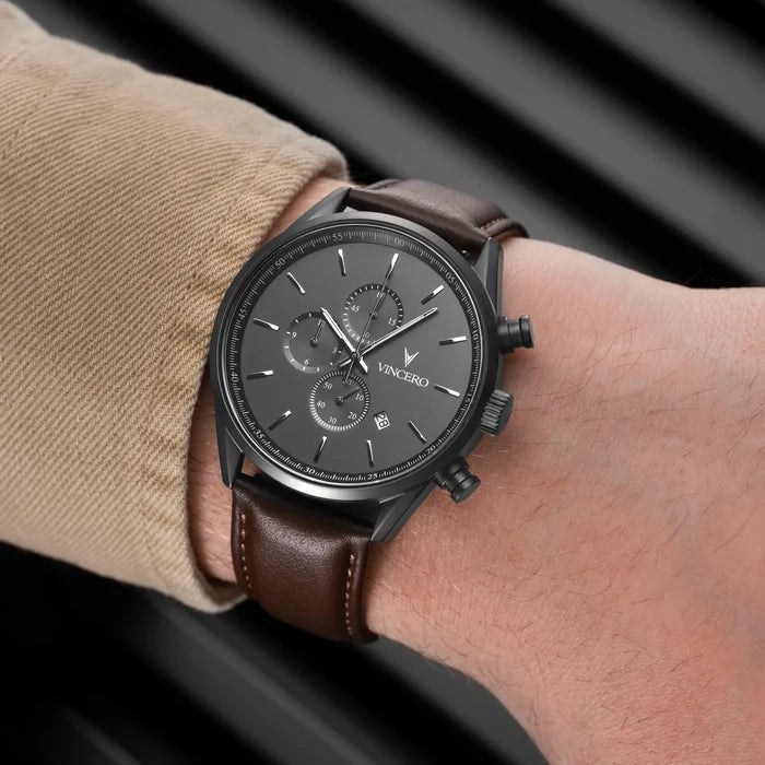Black wristwatch with brown leather strap on a wrist, brand 'Vincero' visible