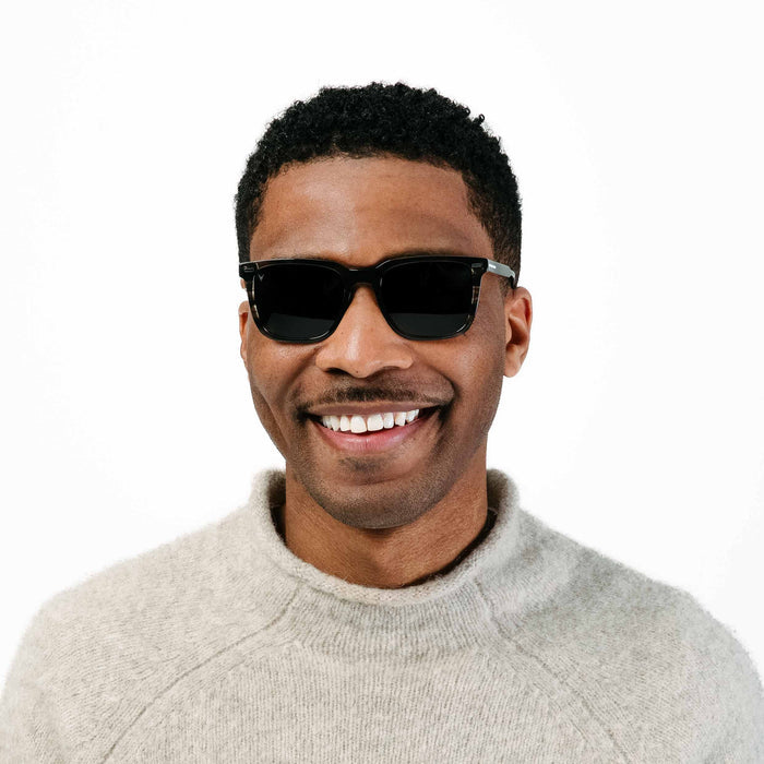 Man wearing sunglasses and a light gray sweater on a white background