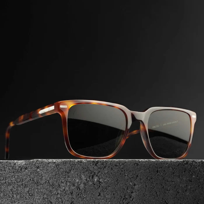 Sunglasses with tortoiseshell frame and dark lenses on a black background