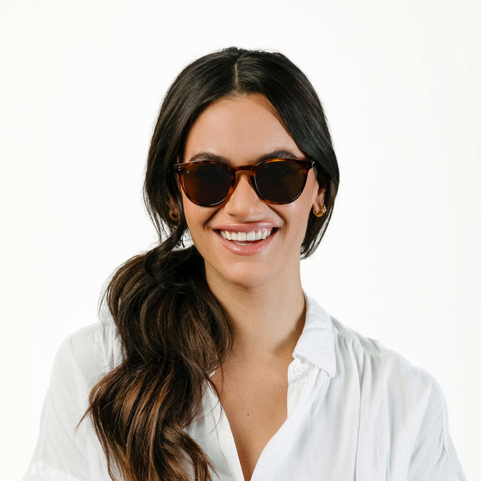 Woman wearing sunglasses and a white shirt on a white background
