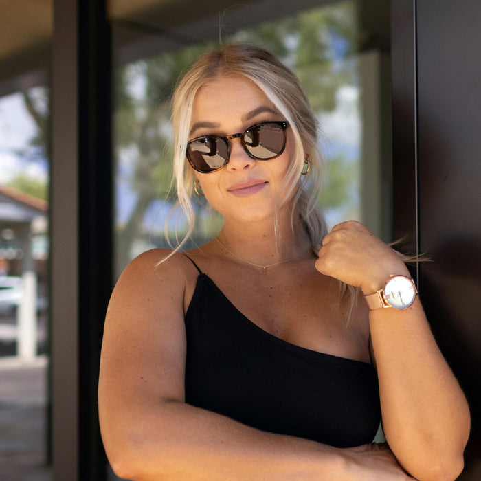 Woman wearing sunglasses and a black top, standing outdoors.