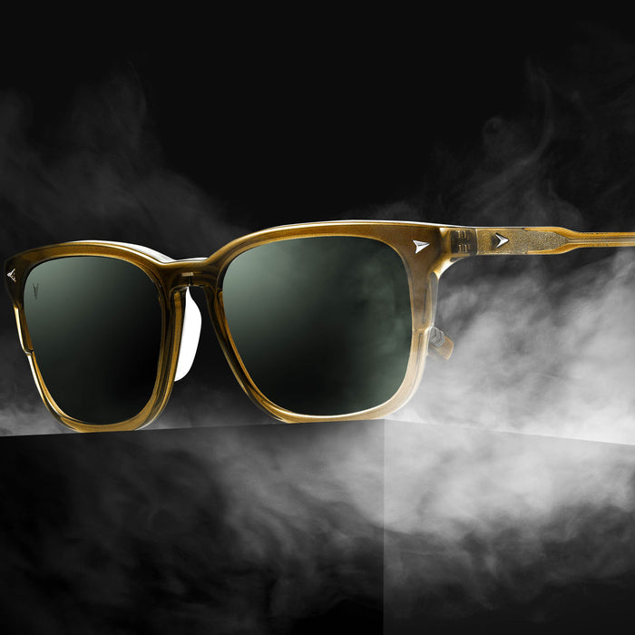 Gold-framed sunglasses with dark lenses on a smoky background