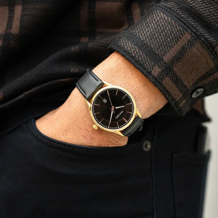 Person wearing a black watch with gold accents on a blurred background