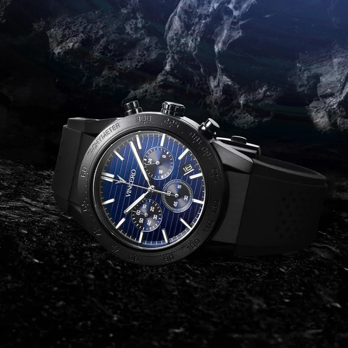 Luxury watch with blue face and black casing on a dark textured surface