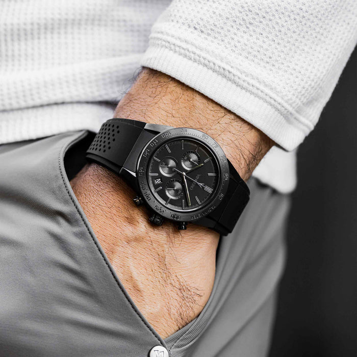 Black watch on a person's wrist with a white shirt and gray pants