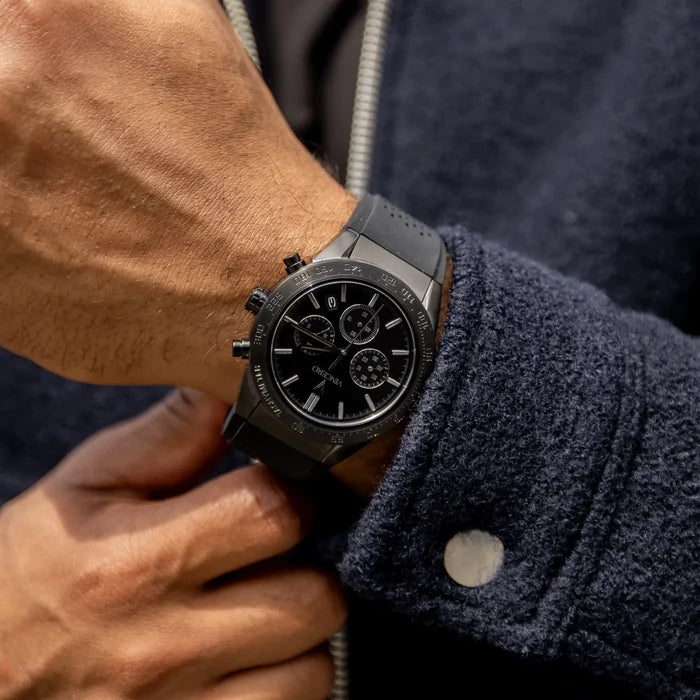 Close-up of a person wearing a black watch on a dark jacket.