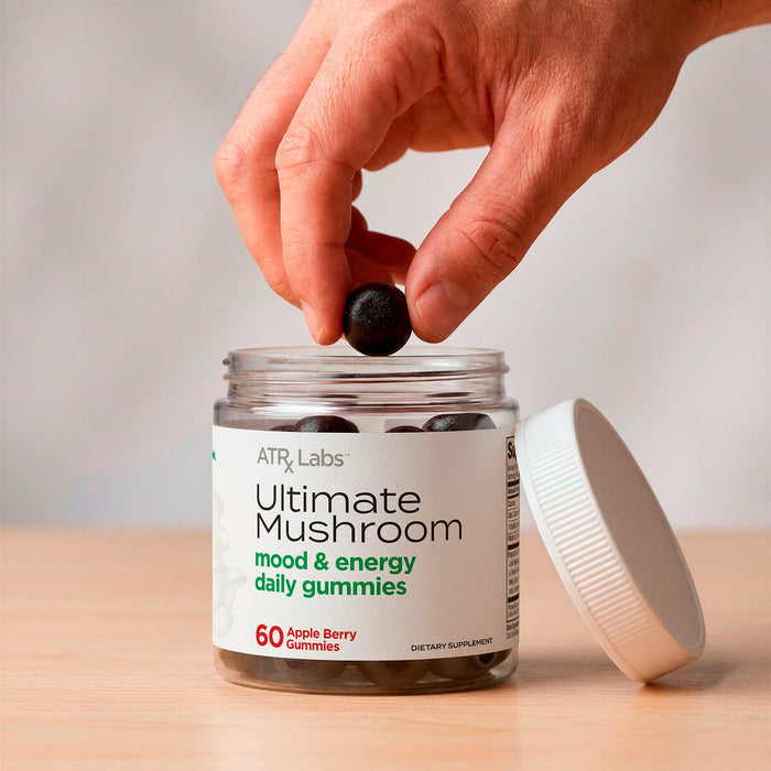 Hand taking a gummy from ATRx Labs Ultimate Mushroom mood and energy daily gummies jar