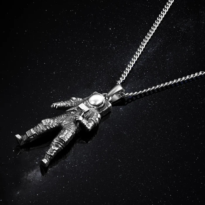 Silver astronaut pendant on a chain against a black background