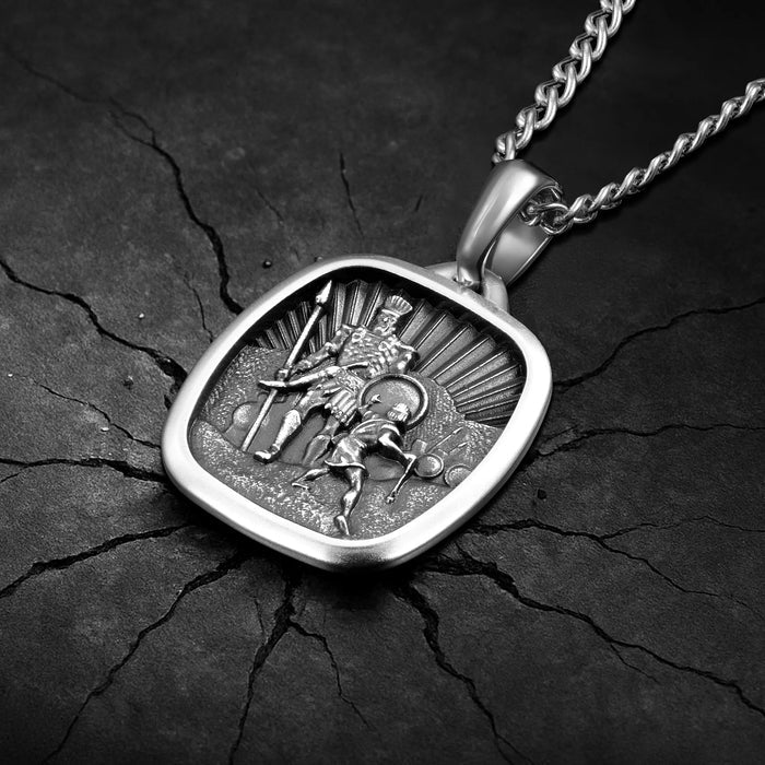Silver pendant with intricate design on a dark, textured surface
