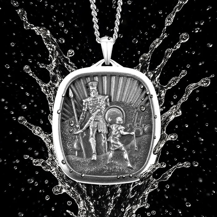Silver pendant with detailed design on a black background with water effect