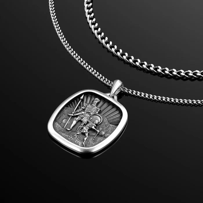 Silver pendant with warrior design on a chain against a black background