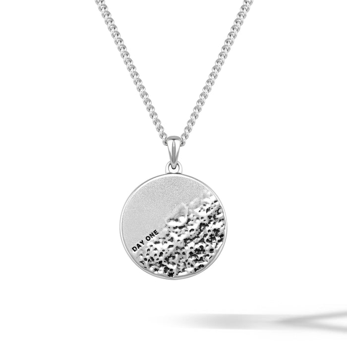 Silver necklace with a round pendant on a white background