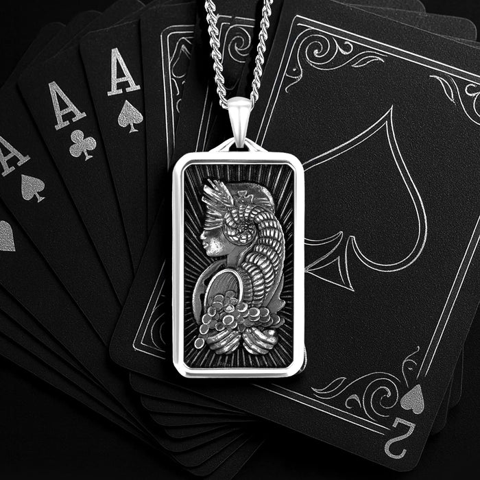Silver pendant with a detailed design on black playing cards