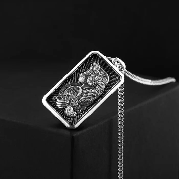 Silver pendant with intricate design on a black background