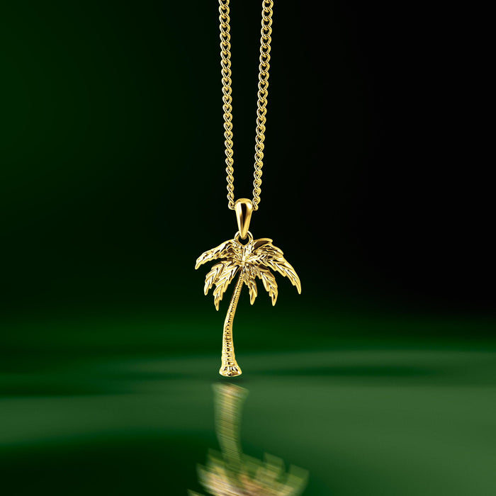 Gold palm tree pendant suspended over green water. A pendant necklace for men.