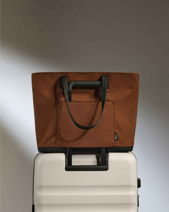 a brown bag on top of a white suitcase