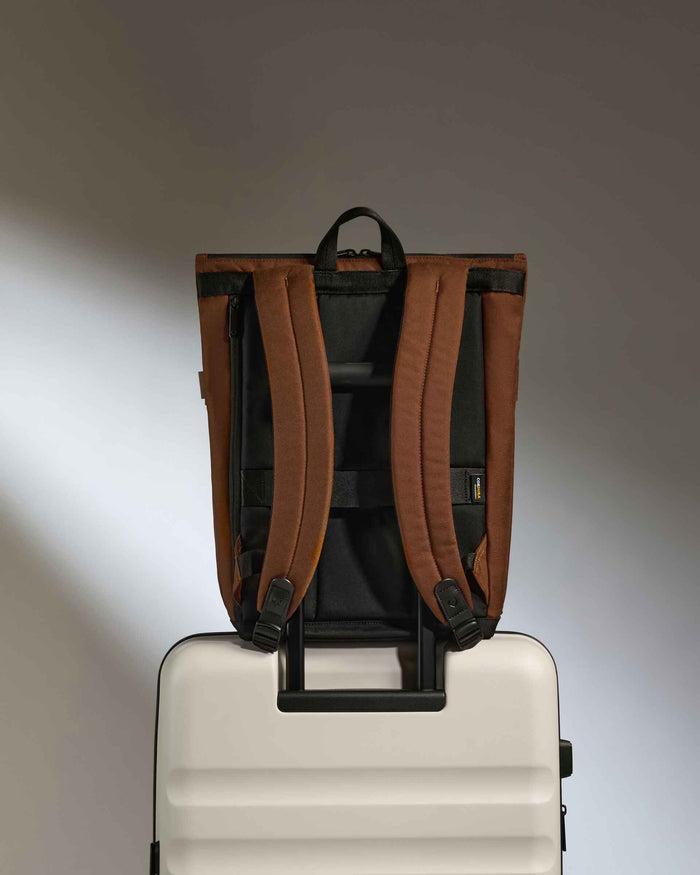 a brown backpack on top of a white suitcase