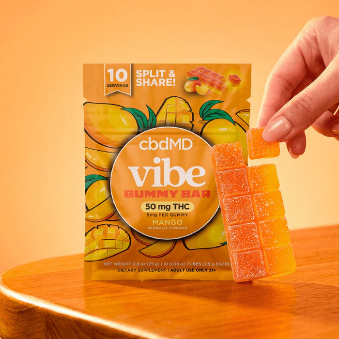 Mango flavored THC gummy bar in orange packaging with a hand holding a gummy square