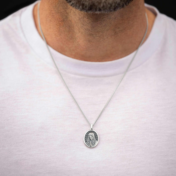 Silver necklace with a pendant worn by a person on a white shirt